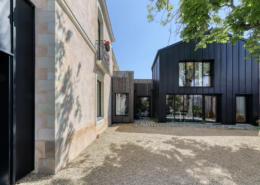 Cour intérieure : liaison en bardage bois clair entre la maison ancienne en pierre et l'extension en bardage zinc noir