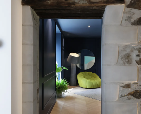 Entrée en pierre ancienne avec poutre bois apparente, ouvrant sur le salon aux murs bleu nuit
