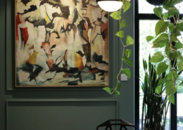 Salle à manger de l'extension avec mur vert bouteille, tableau abstrait et table en marbre