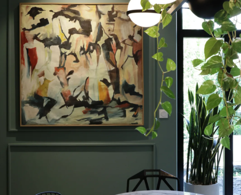 Salle à manger de l'extension avec mur vert bouteille, tableau abstrait et table en marbre