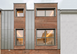 Vue rapprochée de la façade en bardage bois agricole et zinc, insérée dans une ruelle étroite au Pellerin